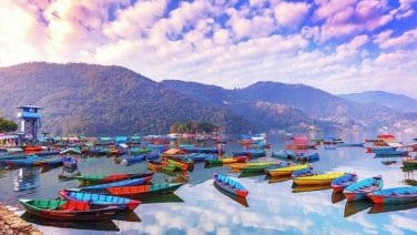 Vibrant Pokhara nightlife with neon lights, music, and Himalayan backdrop, bustling with energy.