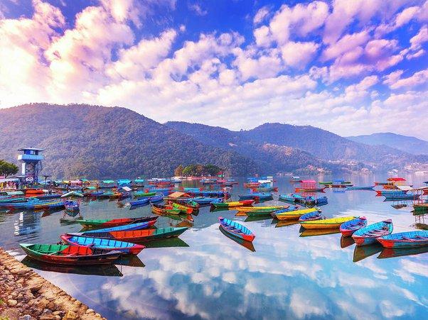 Vibrant Pokhara nightlife with neon lights, music, and Himalayan backdrop, bustling with energy.