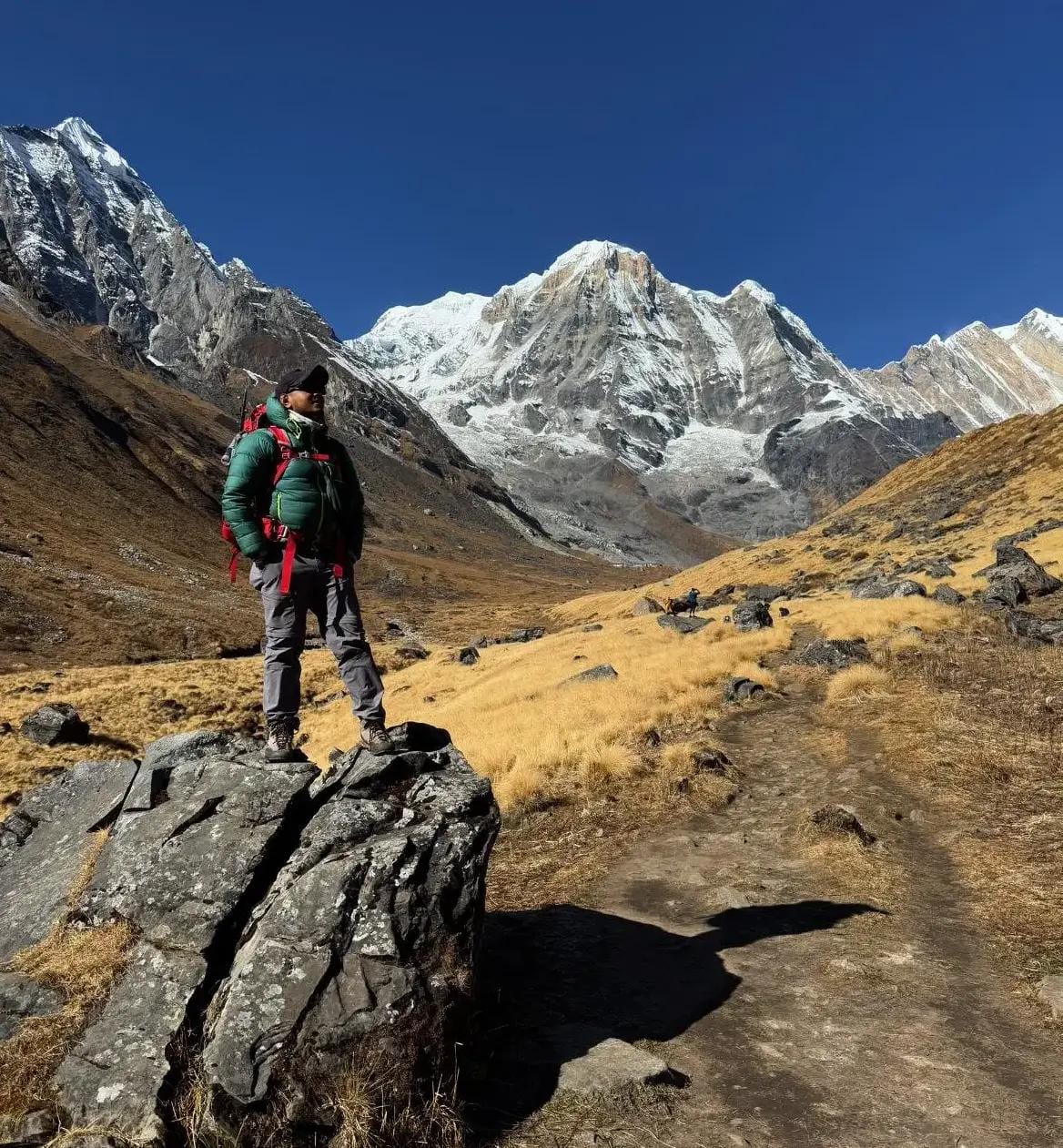 Solo trekker in silhouette reflecting at sunrise over Annapurna peaks, a moment of enlightenment captured in detail.
